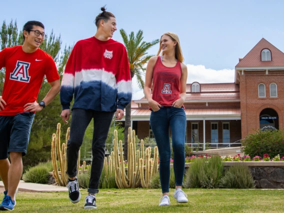 3 students walking and talking in front of old main