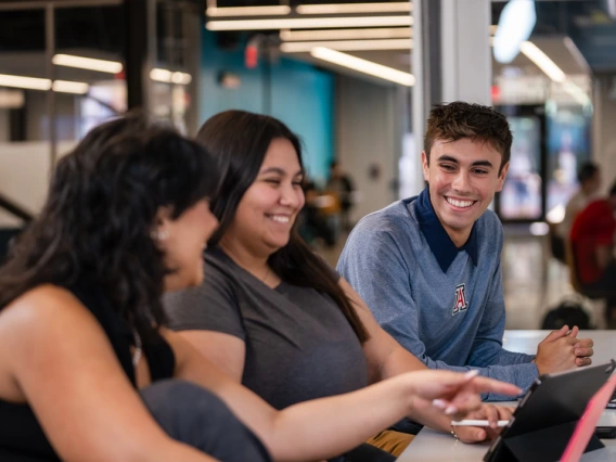3 students sitting together smiling and talking