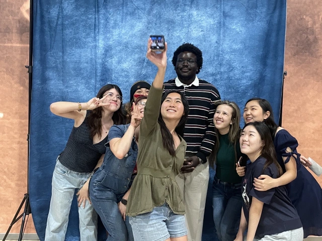 Image of group of students in front of backdrop taking a selfie